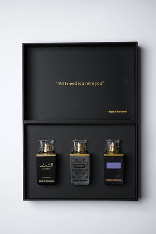 Three perfume bottles in a black display case with a quote above on a white background by Atyab Al Marshoud.